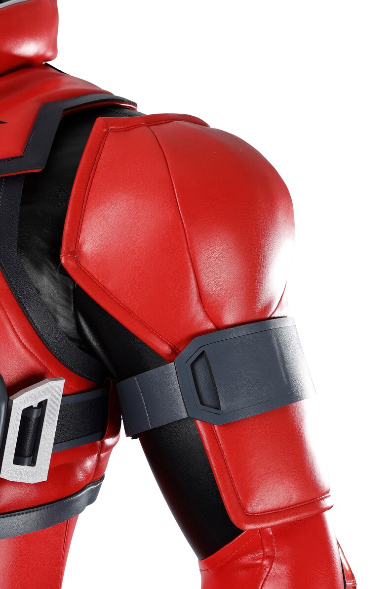 Pu&ograve; includere: Una giacca da costume rossa e nera con spalline imbottite, una fascia grigio scuro sul bicipite e una fibbia rettangolare color argento sul petto. Il capo &egrave; realizzato in un materiale liscio simile alla pelle con cuciture strutturate.