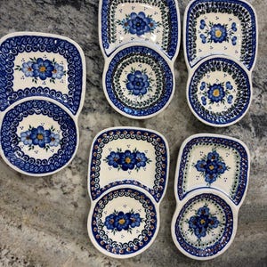 May include: Five ceramic serving dishes, each featuring a rectangular section attached to a circular section. The white surfaces are decorated with blue floral patterns, yellow centers, and intricate blue and green geometric borders around the edges.