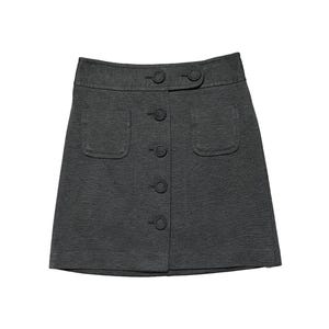 May include: A dark gray mini skirt featuring a high waistband with two decorative buttons, a vertical row of four matching buttons down the center front, and two patch pockets on the front. The skirt has a structured, A-line silhouette.