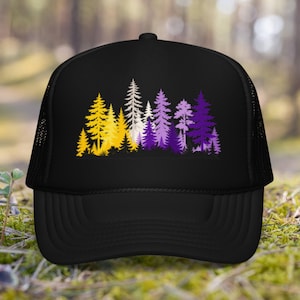 May include: A black trucker cap featuring a graphic print of a forest of pine trees. The trees are coloured in a gradient transition from yellow on the left, to white in the centre, and purple on the right side, set against the solid black fabric.