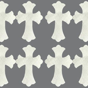 May include: Eight identical white cross-shaped patches arranged in two rows of four. Each cross features a textured surface with rounded, flared ends and a central vertical and horizontal bar design, presented against a solid gray background.