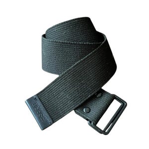 May include: A black canvas belt featuring a woven texture and a double D-ring metal buckle. The end of the belt has a black leather-like tip embossed with the word ESPRIT. The belt is coiled, showing the durable fabric construction and hardware.