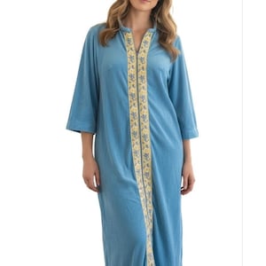 May include: A long, light blue robe featuring three-quarter length sleeves and a stand-up collar. A vertical panel runs down the center front, decorated with a yellow and blue floral pattern. The garment includes a full-length front zipper closure.