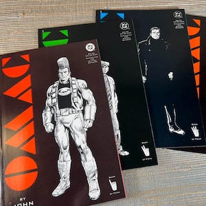 May include: Four comic books with black covers and illustrations. The first comic book has a red and orange design with a muscular character. The other three have black covers with white illustrations of characters. The comic books are labeled "Book of Four."