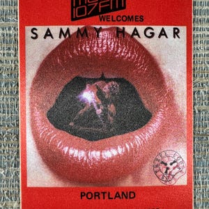 May include: A red and white concert pass for Sammy Hagar, hosted by Magic 107 FM in Portland. The pass features a close-up of red lips with a black interior. The date of the event is March 31 - April 1, 1983.