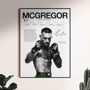以下が含まれることがあります： UFCグローブを着用したコナー・マクレガーのポートレートが描かれた白黒のポスター。白い背景に、名前、アイルランド国旗、チャンピオンタイトルのリスト、経歴の段落、署名、引用文が記載されています。