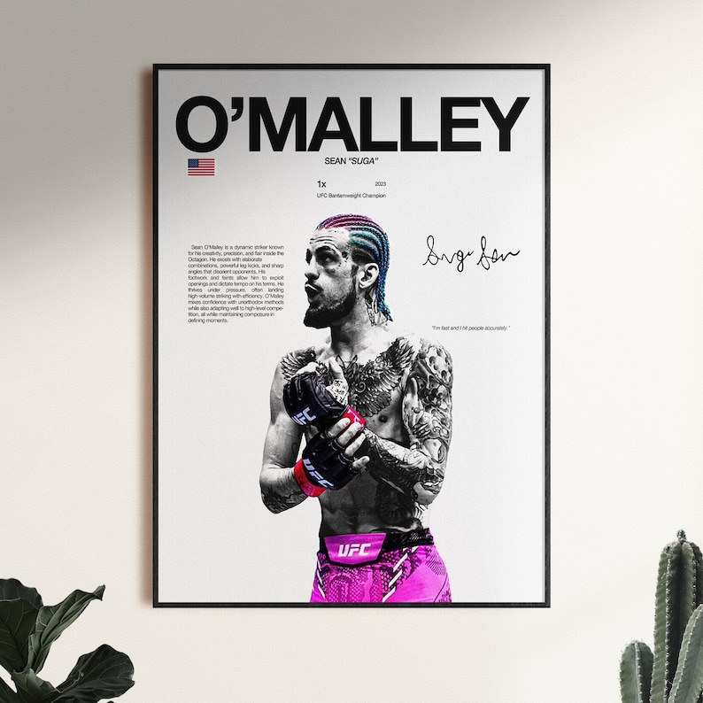 Op de afbeelding: Een ingelijste poster met een zwart-witfoto van Sean O'Malley met roze en blauw haar, dragend zwarte UFC-handschoenen en een roze broek. De tekst bevat O'MALLEY, SEAN SUGA, 1x UFC Bantamweight Champion 2023 en een handtekening.