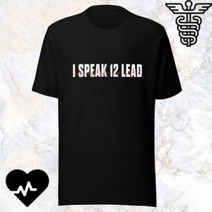 Könnte beinhalten: Ein schwarzes Kurzarm-T-Shirt mit dem weißen Text I SPEAK 12 LEAD und einer roten EKG-Herzrhythmuslinie, die durch die Buchstaben verläuft. Ein weißes Äskulapstab-Symbol befindet sich oben rechts und ein schwarzes Herz mit EKG-Linie unten.