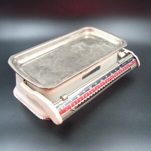 Puede incluir: Balanza de cocina vintage de color crema con una bandeja de acero inoxidable. La balanza presenta un dial de medición rojo y negro. La balanza está diseñada para medir hasta 2800 gramos.