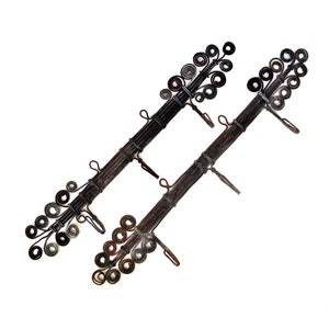Puede incluir: Dos barras de cortina decorativas de metal. Cada barra es de color marrón oscuro con una serie de detalles metálicos en espiral y pequeños ganchos. Las barras están anguladas sobre un fondo blanco, mostrando su intrincado diseño y artesanía.