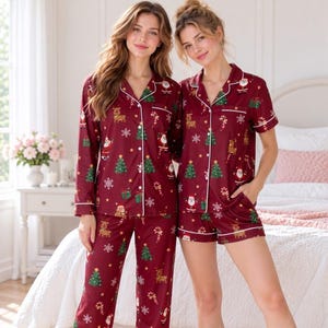 Può includere: Un set pigiama a due pezzi in rosso scuro con una stampa natalizia ripetuta di Babbo Natale, renne, alberi di Natale, fiocchi di neve e bastoncini di zucchero. Il set include una camicia abbottonata con colletto e profili bianchi.