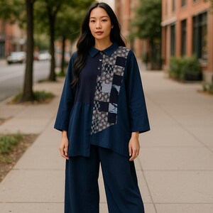 May include: A dark navy blue long-sleeved shirt with a collar and a button-down placket, featuring a vertical panel of patchwork fabric with various geometric and floral patterns in shades of blue, white, and grey, paired with matching wide-leg trousers.