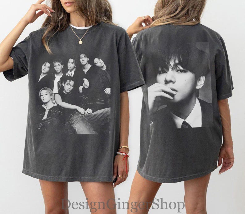 Puede incluir: Una camiseta de manga corta gris carb&oacute;n con un estampado gr&aacute;fico en blanco y negro de un grupo de siete personas en la parte delantera y un gran retrato en blanco y negro de una persona en la parte trasera. Tiene cuello redondo y corte holgado.