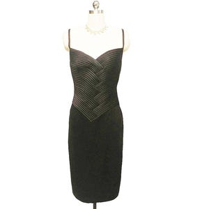 May include: A black sleeveless dress with a fitted bodice and a pleated design. The dress has a sweetheart neckline and a straight skirt.