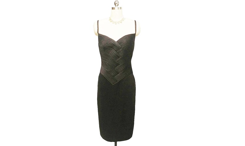 May include: A black sleeveless dress with a fitted bodice and a pleated design. The dress has a sweetheart neckline and a straight skirt.