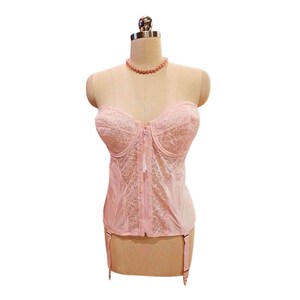 May include: A pink lace corset with a zipper closure and garter straps.