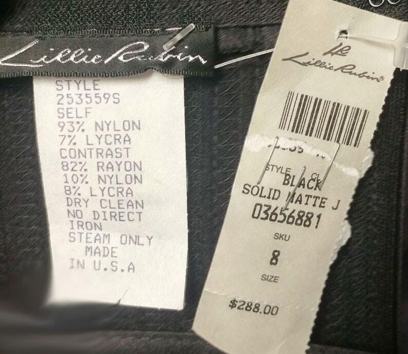 May include: A black dress with a white tag that says "Lillie Rubin" and has the style number 2535595. The tag also lists the fabric composition and care instructions. The dress is priced at $288.00.