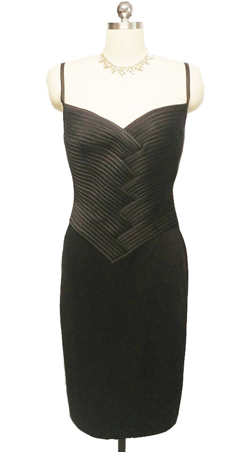 May include: A black sleeveless dress with a pleated bodice and a fitted skirt.
