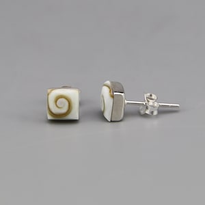 May include: A pair of square stud earrings featuring a white and brown spiral pattern on the front face. The earrings are set in a silver-toned metal frame with a standard post and butterfly clutch backing mechanism for secure attachment.