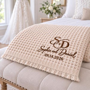 Parchment waffle throw featuring a personalized wedding embroidery positioned near the lower corner.
The design includes a large intertwined “S + D” monogram, “Sophia and Daniel” in script, and the date “09.14.2026” below.
All details are embroidered in deep brown thread for a clear contrast against the light Parchment fabric.
The elegant corner placement creates a personalized monogrammed wedding throw design.