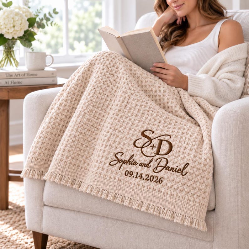 Parchment waffle throw featuring a personalized wedding embroidery positioned near the lower corner.
The design includes a large intertwined “S + D” monogram, “Sophia and Daniel” in script, and the date “09.14.2026” below.
All details are embroidered in deep brown thread for a clear contrast against the light Parchment fabric.
The elegant corner placement creates a personalized monogrammed wedding throw design.