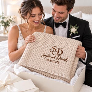 Parchment waffle throw featuring a personalized wedding embroidery positioned near the lower corner.
The design includes a large intertwined “S + D” monogram, “Sophia and Daniel” in script, and the date “09.14.2026” below.
All details are embroidered in deep brown thread for a clear contrast against the light Parchment fabric.
The elegant corner placement creates a personalized monogrammed wedding throw design.