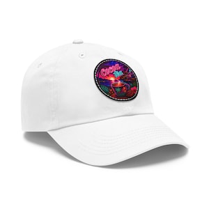 May include: A white baseball cap featuring a circular patch on the front. The patch displays a vibrant, colorful graphic of a steaming mug with the text Cocoa Tea in a neon-style font, set against a tropical sunset background with palm trees.