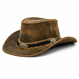 May include: A brown distressed leather hat with a wide brim and a pinched crown. The hat features a decorative band with black leaf-shaped accents and two silver-toned circular concho embellishments. Three small metal ventilation eyelets are visible.