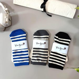 May include: Three pairs of striped socks, each wrapped in a white paper band labelled Viva Barre. The socks feature horizontal stripes in blue and white, dark grey and white, and black and white. Each pair is folded flat and neatly presented.