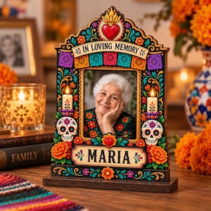 May include: A rectangular wooden memorial photo frame featuring a colorful Day of the Dead theme with sugar skulls, marigold flowers, and a sacred heart. The frame displays the text IN LOVING MEMORY and MARIA, with two integrated candle holders.