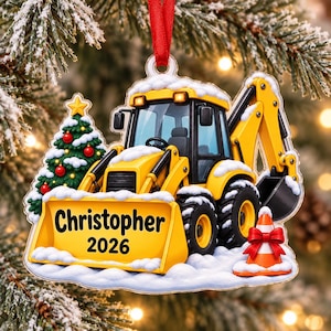 May include: A flat, hanging Christmas ornament featuring a yellow backhoe loader covered in snow. The front blade displays the name Christopher and the year 2026 in black text. A decorated Christmas tree and an orange traffic cone are included.