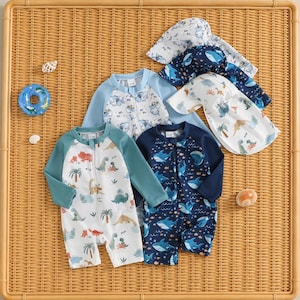 Puede incluir: Dos trajes de baño de manga larga con cremalleras frontales y dos sombreros de sol a juego. Un traje presenta una base blanca con estampados coloridos de dinosaurios y palmeras con mangas verde azulado, el otro una base azul oscuro.