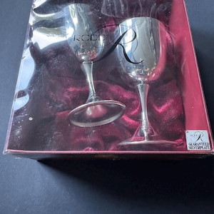May include: Two silver-plated goblets with smooth, reflective surfaces housed in a rectangular box with a deep red velvet lining. The box features the Rodd brand logo and the text Guaranteed Silverplate printed on the front and a small corner label.