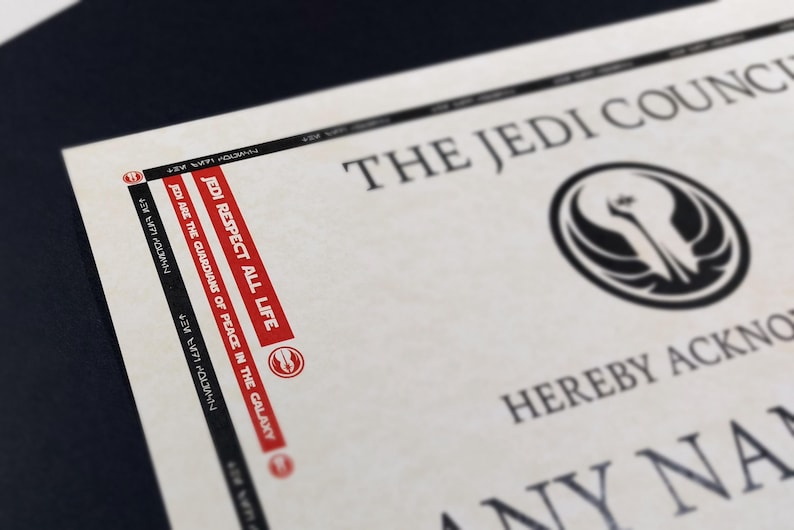 May include: A white certificate with black text that reads "The Jedi Council" and a black symbol with a white background. The text "Jedi Respect All Life" is printed in red on the side of the certificate.