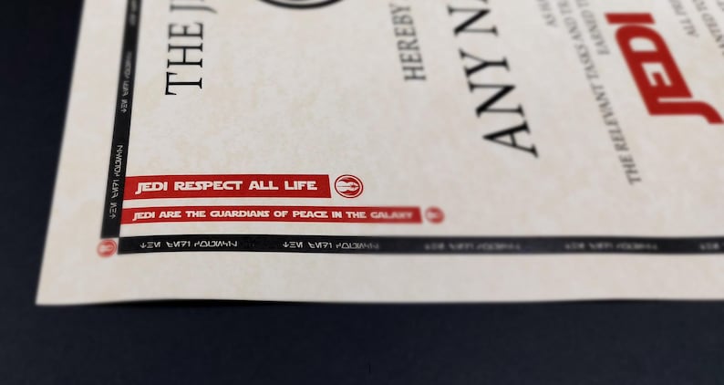 May include: A close-up of a certificate with the text "JEDI RESPECT ALL LIFE" and "JEDI ARE THE GUARDIANS OF PEACE IN THE GALAXY" printed in red on a white background. The certificate also includes the text "THE JEDI" and "HEREBY ANY NAME THE RELEVANT TASKS AND EARNED JEDI ALL PR"