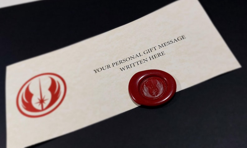 May include: A white card with a red Star Wars Rebel Alliance symbol and the text "YOUR PERSONAL GIFT MESSAGE WRITTEN HERE". A red wax seal with the Rebel Alliance symbol is on the card.