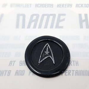 May include: A black wax seal with a silver Starfleet insignia. The text "THE FACULTY OF STARFLEET ACADEMY HEREBY ACKNOWLEDGE THAT ANY NAME HERE" is visible in the background.