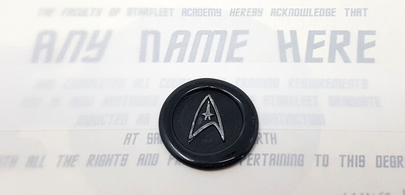 May include: A black wax seal with a silver Starfleet insignia. The text "THE FACULTY OF STARFLEET ACADEMY HEREBY ACKNOWLEDGE THAT ANY NAME HERE" is visible in the background.