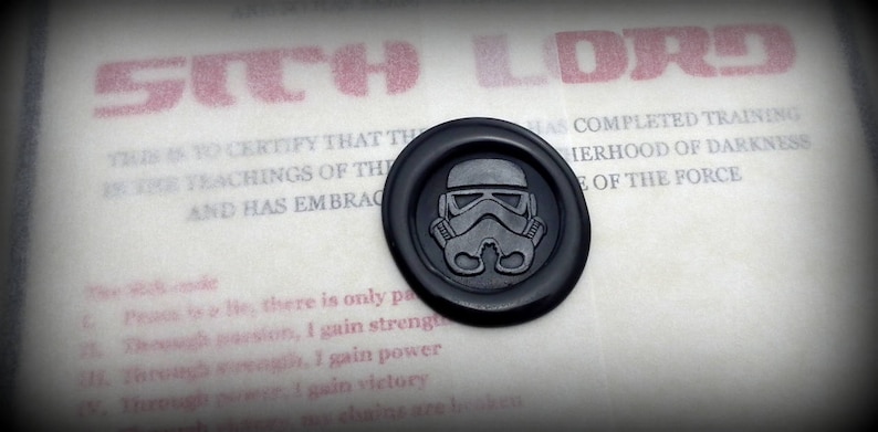 May include: A black wax seal with a white Star Wars Stormtrooper helmet design. The seal is on a white background with the text "SITH LORD" in red letters above it. The text below the seal reads "THIS IS TO CERTIFY THAT THE... HAS COMPLETED TRAINING IN THE... HERHOOD OF DARKNESS... OF THE FORCE."