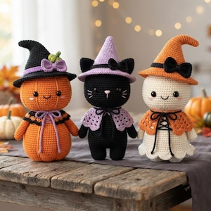 Puede incluir: Tres muñecos de ganchillo que incluyen una calabaza con sombrero de bruja negro, un gato negro con sombrero de bruja lavanda y un fantasma blanco con sombrero de bruja naranja. Cada muñeco tiene ojos de botón negros, un lazo y un cuello.