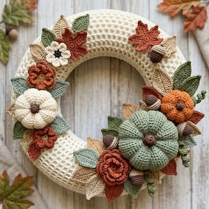 Pode incluir: Uma guirlanda circular feita de malha de crochê na cor creme, decorada com abóboras de crochê em branco, laranja e verde sálvia, além de flores, bolotas marrons e várias folhas em tons de verde, bege e laranja ferrugem.