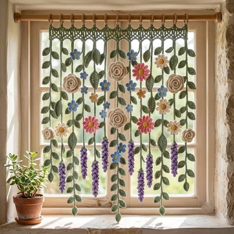 May include: A crochet window valance featuring hanging green vines with various flowers including beige roses, pink daisies, small blue blossoms, and purple lavender-like clusters, all suspended from a wooden rod with matching rings.