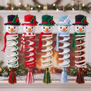 May include: Five crocheted snowman ornaments hanging vertically. Each snowman features a top hat, a scarf, and a spiral-shaped body ending in a tassel. The hats and scarves vary in color, including red, green, blue, and black with holly accents.