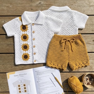 May include: A white crocheted short-sleeved shirt with a vertical row of four yellow and brown sunflower motifs and five wooden buttons, paired with mustard yellow crocheted shorts featuring a drawstring waist and a scalloped hemline.
