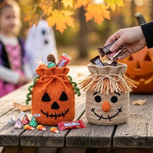May include: Two crochet drawstring bags for Halloween candy. One is orange with a jack-o'-lantern face and green curly accents. The other is tan with a scarecrow face and raffia-style fringe. Both bags are filled with assorted candy bars.