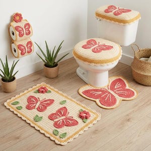 May include: A crochet bathroom set in cream, featuring pink butterfly and flower motifs. The set includes a rectangular rug, a toilet seat cover, a tank cover, and a wall-mounted toilet paper holder, all with scalloped edges and textured details.