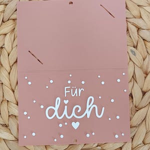 Peut inclure: Une carte rectangulaire rose poudr&eacute; avec le texte blanc F&uuml;r dich, signifiant Pour toi, centr&eacute; sur la moiti&eacute; inf&eacute;rieure. La carte est d&eacute;cor&eacute;e de petits points blancs et d'une ic&ocirc;ne de c&oelig;ur blanc dispers&eacute;s sur la partie inf&eacute;rieure.