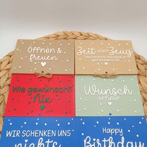 Peut inclure: Six cartes rectangulaires de couleur beige, rouge, vert clair et bleu, orn&eacute;es de textes en blanc ou vert et de petits c&oelig;urs. Les cartes portent les inscriptions "&Ouml;ffnen & freuen," "Zeit statt Zeug," "Wie gew&uuml;nscht: Nix," "Wunsch erf&uuml;ller," "WIR SCHENKEN UNS nichts" et "Happy Birthday."