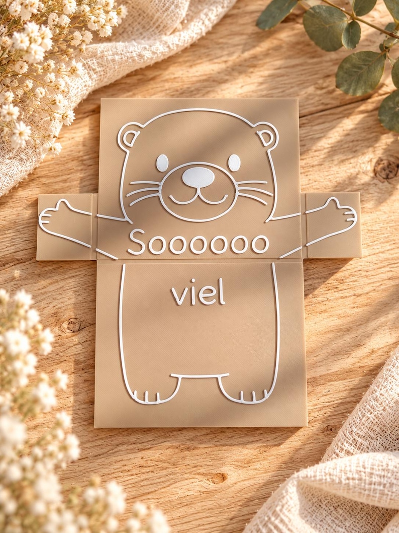 May include: A tan rectangular plaque featuring a white line art illustration of a bear with outstretched arms. The text "Soooooo" is printed above the bear's midsection, and the word "viel" is printed below it in white lettering.