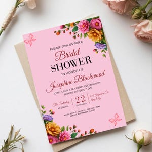 Custom bridal shower invitation displayed on a marble surface with romantic botanical accents and feminine party stationery
